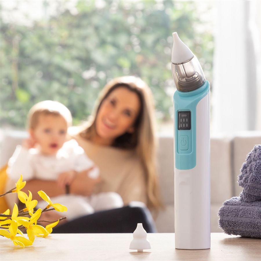 Madre con su bebé en el salón y el aspirador nasal sobre la mesa
